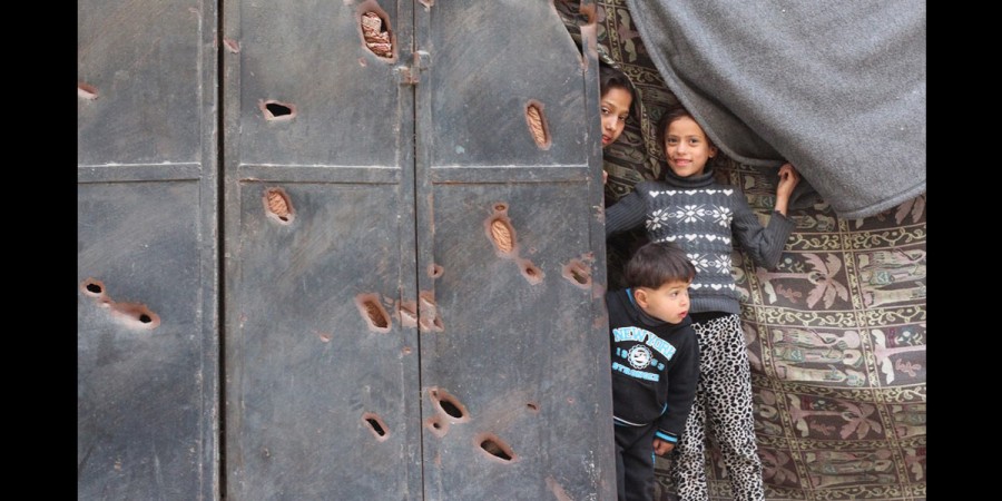 Three children stand in front of their house, which was damaged during the last war on Gaza. ©Mohamed Mousa
