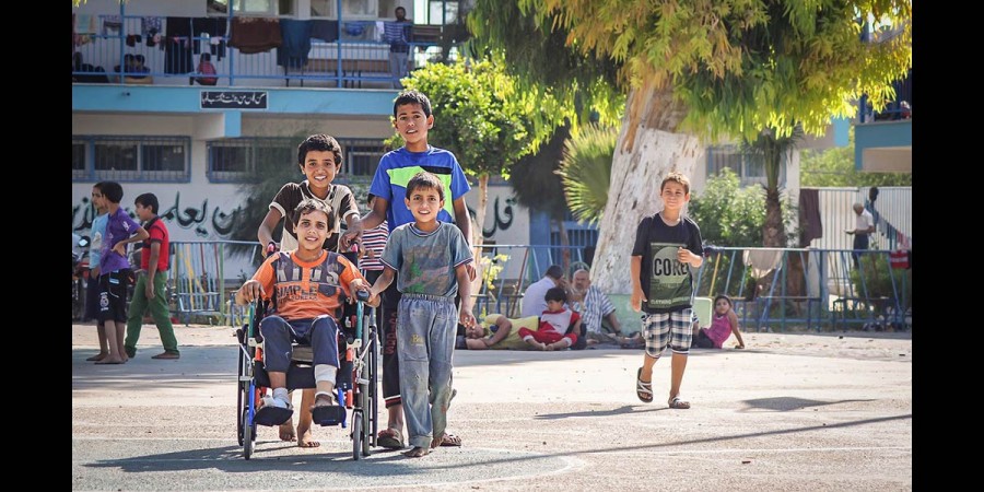 A disabled child, his cousins and friends stand in front of a house no longer fit to live in. ©Ibrahim Abou Nada